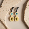 Golden flower-shaped earrings set with blue and yellow bicolor gemstones details Picture